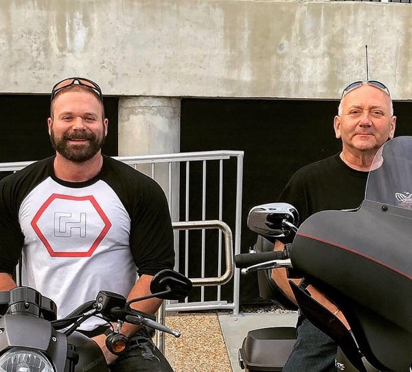 A photo of Kris Cram on a motorcycle beside his father, also on a motorcycle.
